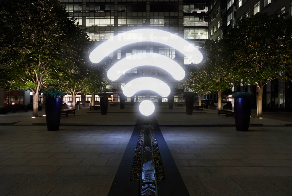 Glowing wifi icon in city street at night, London, UK
