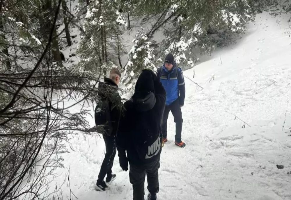 Doi tineri încălțați cu adidași, întorși din drum de jandarmi pe un traseu din Ceahlău